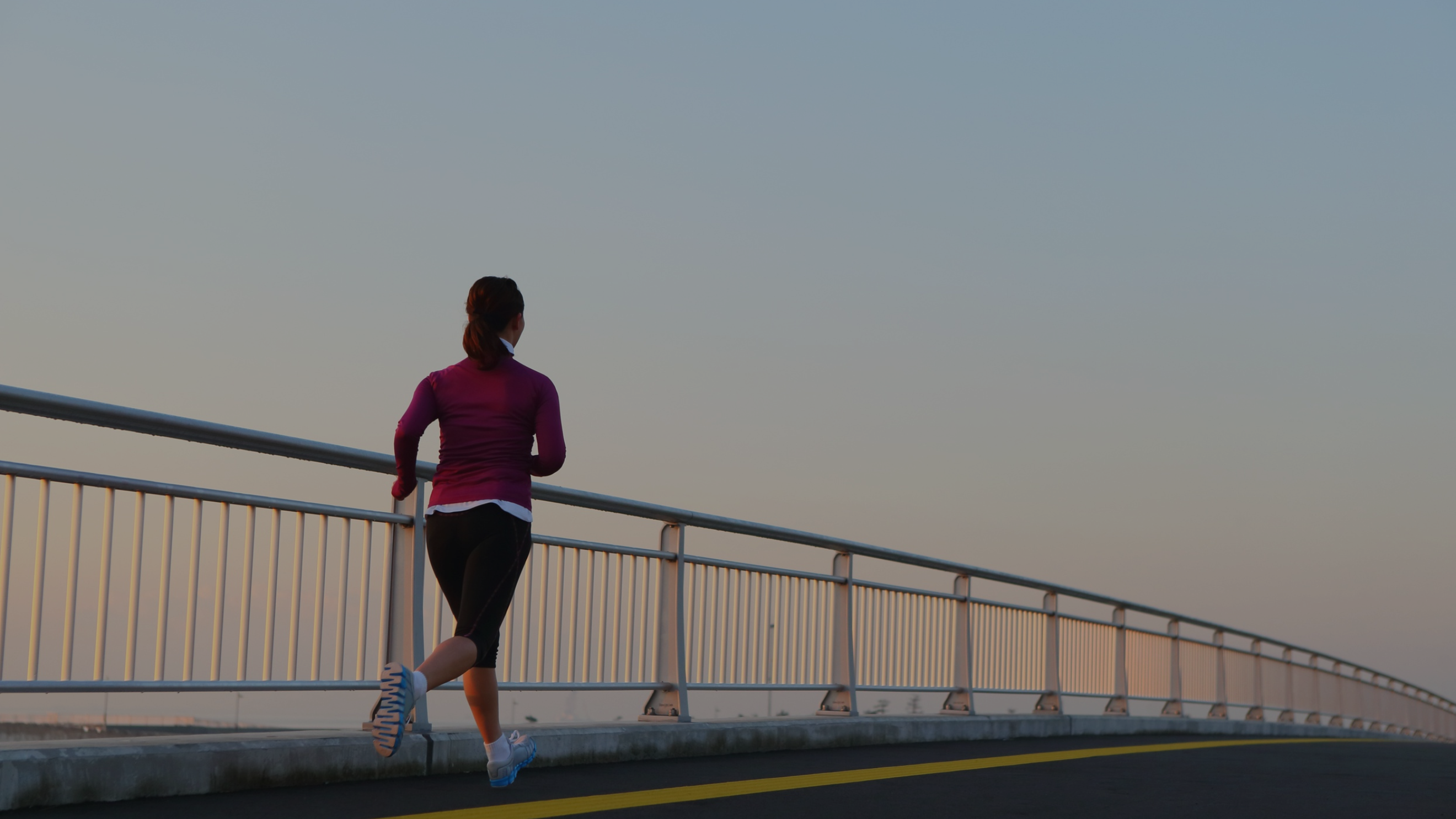 Person running on a bridge during sunset